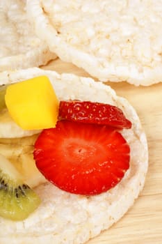 Rice cakes with fresh fruit slices, over a wooden background