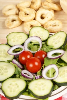 Close-up of an healthy salad, parmesan cheese and taralli over a wooden background. Selective focus. Shallow DOF.