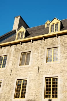 Detail of an old stone house in downtown Quebec City, Canada, against a blue summer sky.