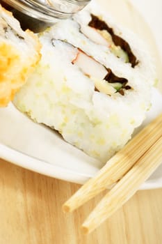 Close-up of a dish with maki sushi rolls with wooden chopsticks and soy sauce. Selective focus.