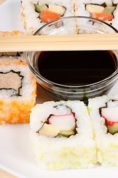 Close-up of a dish with maki sushi roll with wooden chopsticks and soy sauce. Selective focus.