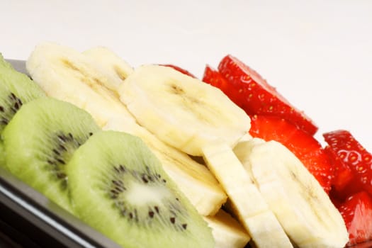 Close up of slices of kiwi, banana and strawberry. It could represent an organic italian flag. 