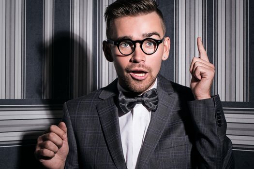 Portrait of a handsome man in a suit and in glasses over a striped background