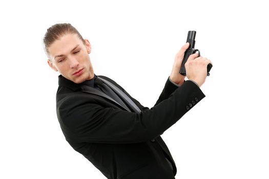 Handsome man in a black suit and a pistol posing over a white background