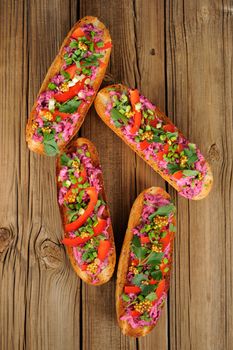 Vegetarian sandwiches with beetroot, bell pepper, parsley and scallion on wooden background vertical top view