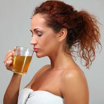 Beautiful middleaged woman in towel with herbal tea
