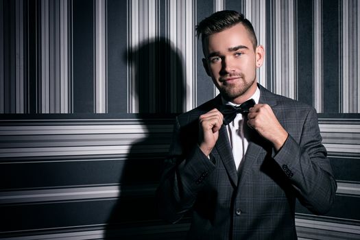 Portrait of a handsome man in a suit and a tie who is posing over a striped background