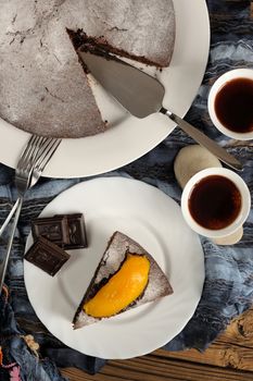 Chocolate cake with mango and black tea on blue cloth top view