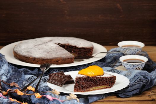 Chocolate cake with mango and black tea on blue cloth with space background horizontal