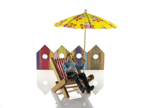 man in chair on the beach with beachhouses as background