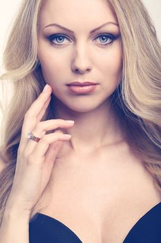 Portrait of a beautiful girl with blonde and curly hair who is posing over a white background