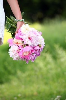 Bouquet of peonies in woman's hand in the park
