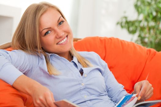 Young blond caucasian woman smiling in orange sofa