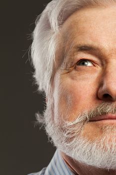 Closeup portrait of elderly man with beard on a black background