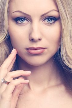 Portrait of a beautiful girl with blonde hair and naked shoulders who is posing over a white background