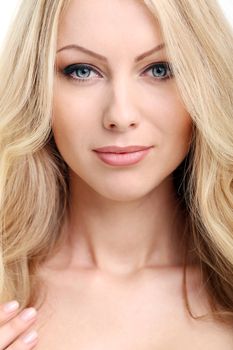 Portrait of a beautiful girl with blonde hair and naked shoulders who is posing over a white background