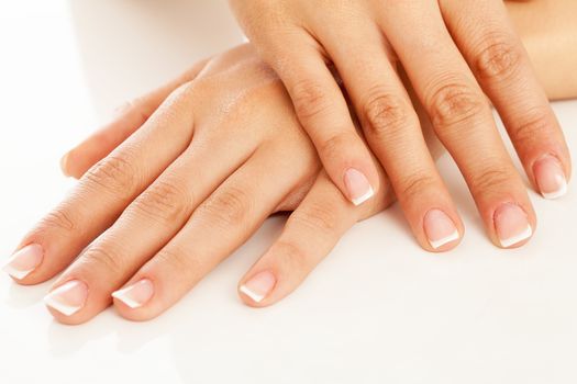 Young woman hands with french manicure over white background