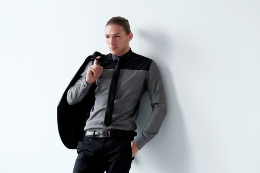 Portrait of a handsome man in a black suit who is posing over a white background