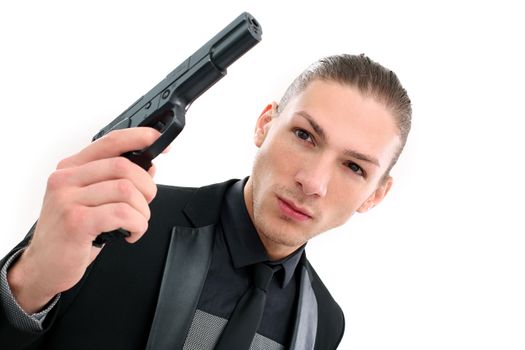 Handsome man in a black suit and a pistol posing over a white background