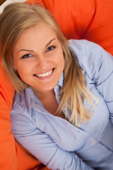 Young blond caucasian woman smiling in orange sofa