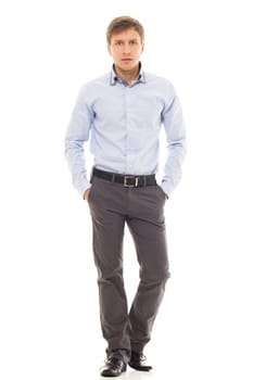 Handsome man in a blue shirt holds his hands in pockets over a white background