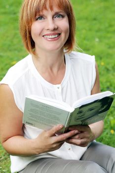 Portrait of an attractive woman who is relaxing at a park while reading a book