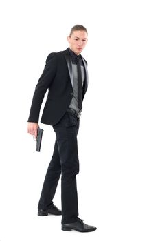 Handsome man in a black suit and a pistol posing over a white background