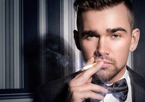 Portrait of a handsome man in a suit with a cigarette