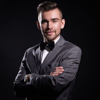 Portrait of a handsome man in a suit who is posing over a black background