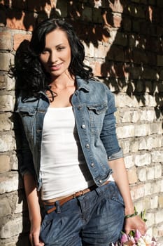 Beautiful young caucasian woman at the brick wall in jeans