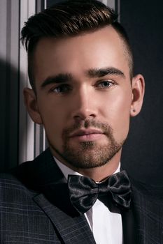 Portrait of a handsome man in a suit and a tie who is posing over a striped background