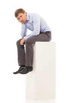 Handsome man in blue shirt and trousers sitting on a cubic sofa that looks like a diagram