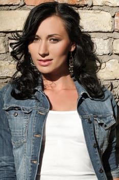 Beautiful young caucasian woman at the brick wall in jeans