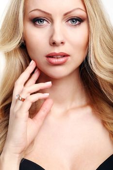 Portrait of a beautiful girl with blonde and curly hair who is posing over a white background