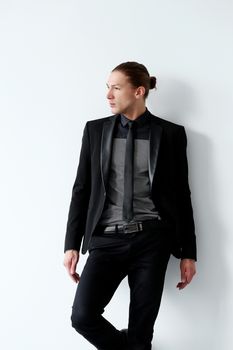 Portrait of a handsome man in a black suit who is posing over a white background