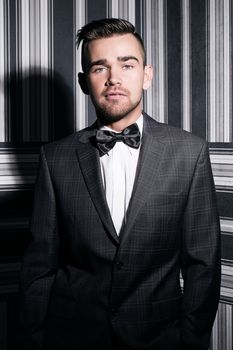 Portrait of a handsome man in a suit and a tie who is posing over a striped background