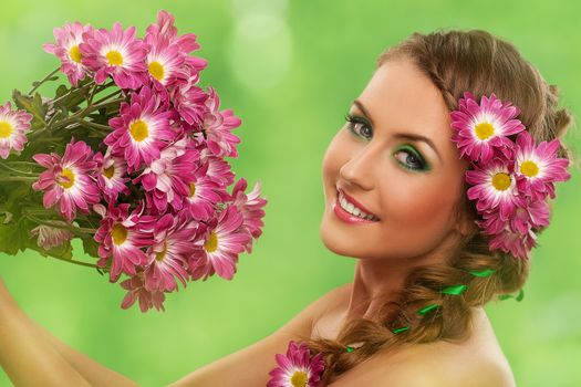 Beautiful woman with makeup and flowers over green background