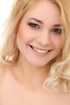 Portrait of a beautiful blonde girl with curly hair who is posing over a white background