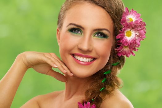 Beautiful woman with makeup and flowers over green background