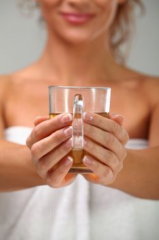 Beautiful middleaged woman in towel with herbal tea