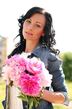 Beautiful caucasian woman in the park with bouquet of peonies