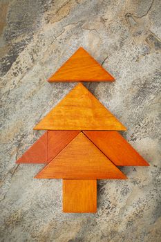 abstract picture of a Christmas tree built from seven tangram wooden pieces over a slate rock background, Christmas holiday concept, artwork created by the photographer