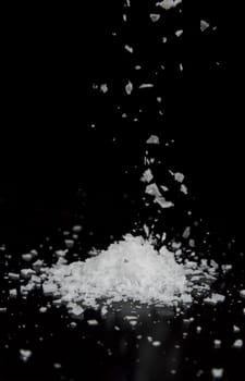 Sea Salt Falling into a Pile with black background.