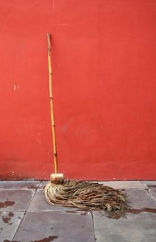 Cleaning mop lean against red wall