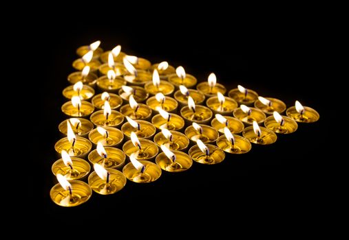 Triangle made of burning candles at night