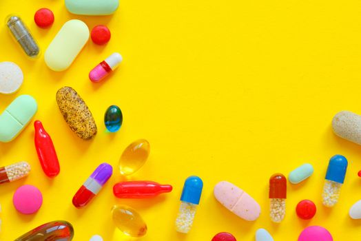 Many colorful pills isolated on yellow background