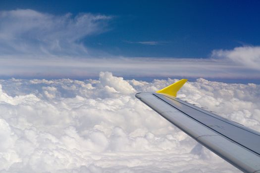 Photo shows details of white clouds, blue sky and plane.