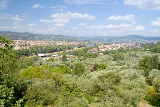 Photo shows a general view onto the city with its roofs, houses and trees.