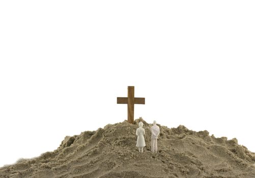 toy couple looking at the wooden holy cross on sand mountain