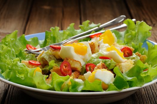 Salad Caesar with eggs, chili pepper and two forks closeup horizontal